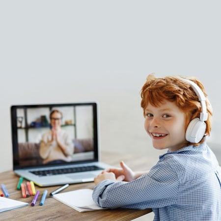 A high school student in a yellow sweater sitting down with a laptop