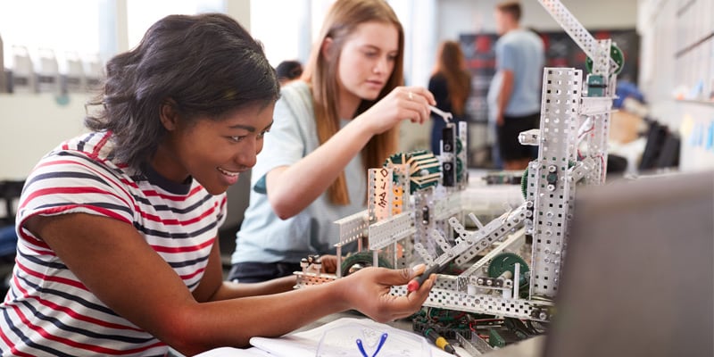 Two students sitting next to eachother and engaging in a building activity