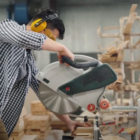 Person operating a miter saw in a woodworking shop.