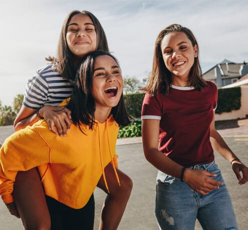 Three happy students walking on a street