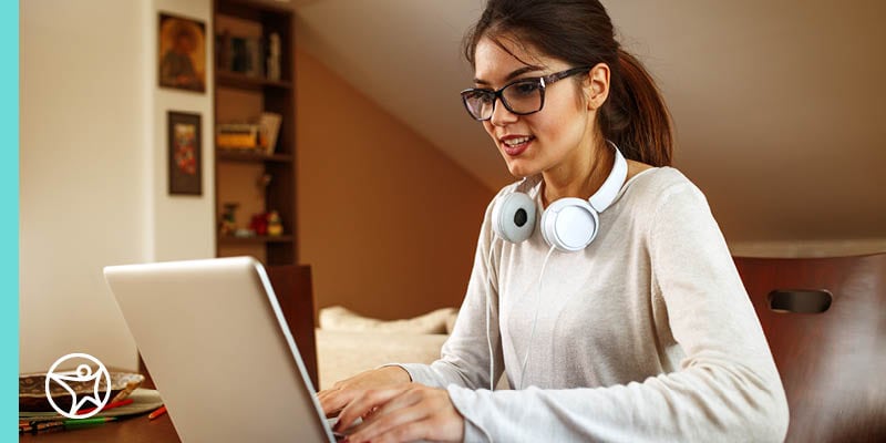 A senior Connections Academy student smiling looking at her computer works on applying for college. 