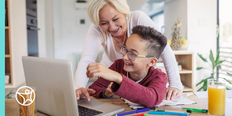 A Learning Coach and online school student smiling and engaging with a laptop