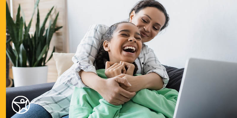 A Learning Coach embracing her student while the sit infront of her laptop