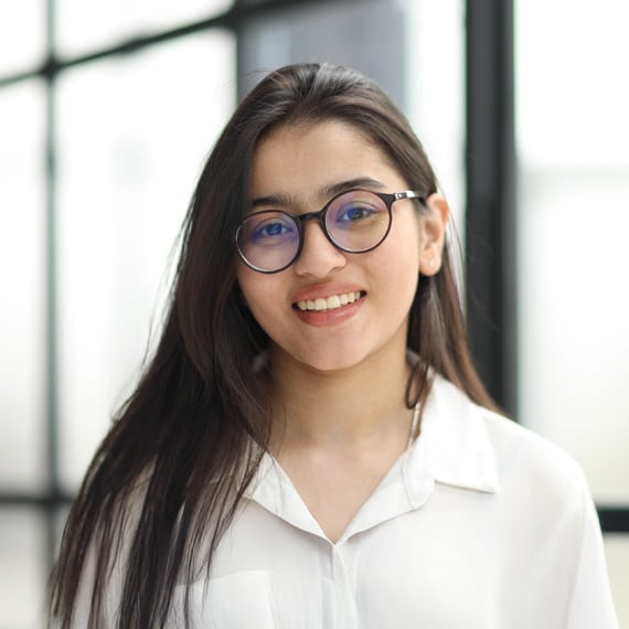 A student with long dark hair wearing a white shirt.